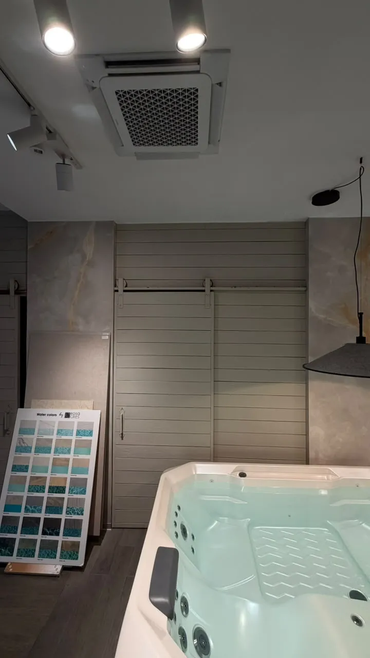 Cassette de 4 vías Samsung en el techo de la sala de experiencia, junto a un muestrario de colores para piscinas
