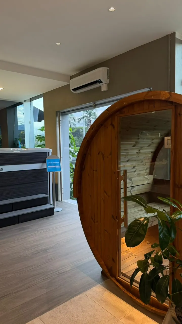Equipo de aire acondicionado de pared sobre la entrada de la sala de experiencia, junto a una sauna de barril