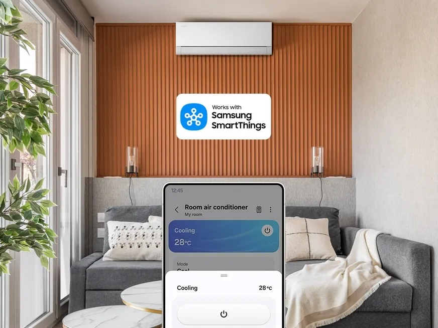 Aire acondicionado WindFree™ de pared de Samsung en una sala, con el sello Works with Samsung SmartThings y un celular que lo controla desde la app